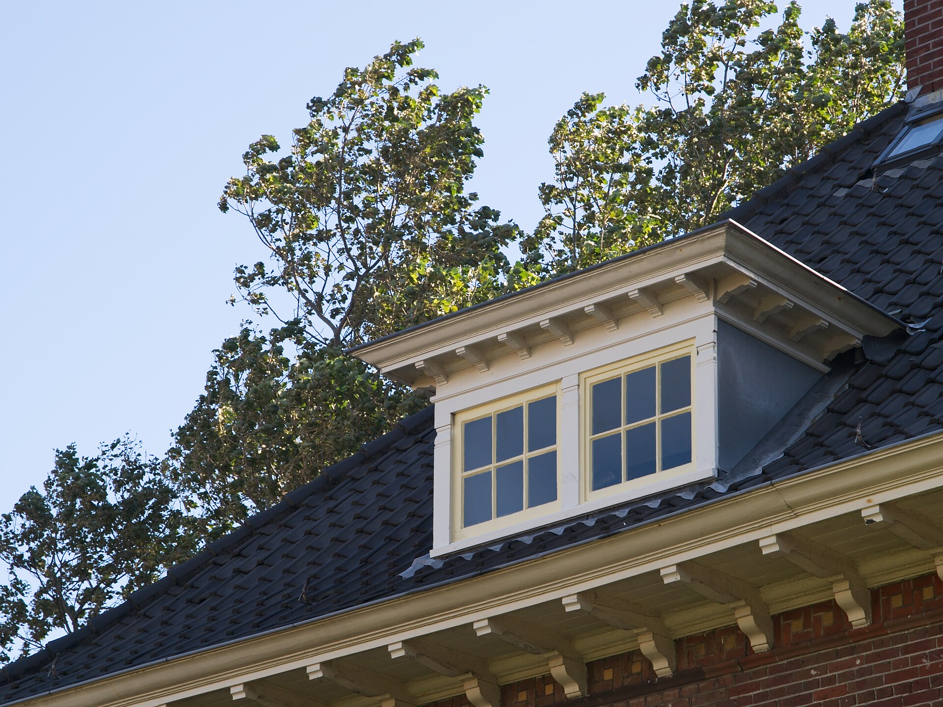 Witte houten dakkapel op een donker pannendak van een woning in Vlissingen